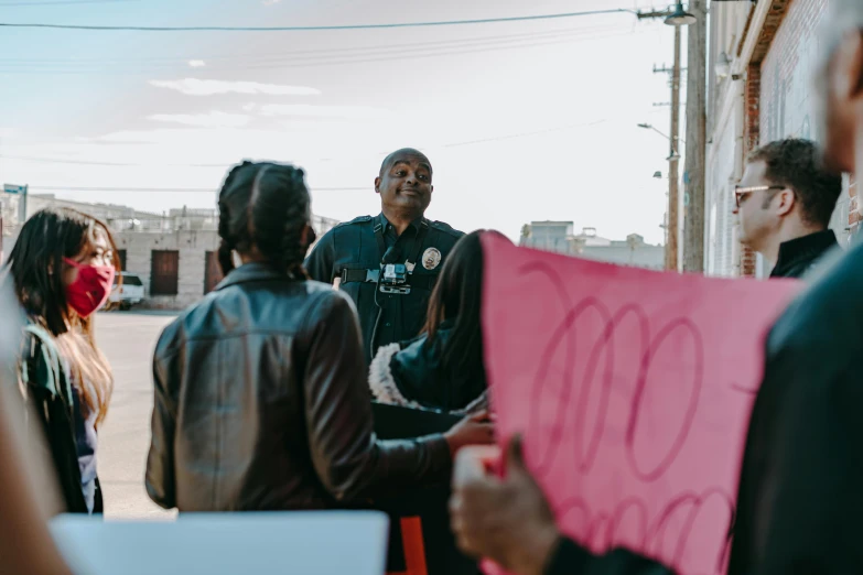 several people are holding a pink sign in front of a building