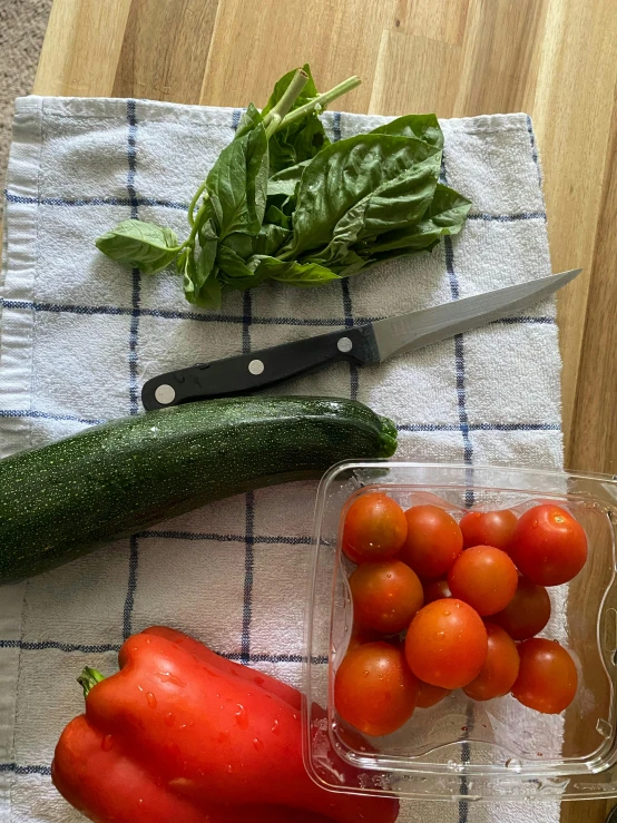 tomatoes, zucchini, and zucchini on a towel next to some green herbs