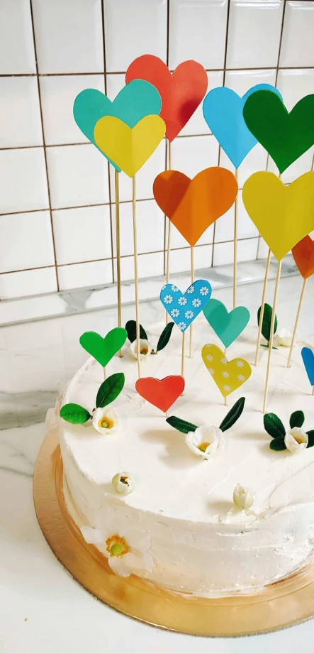 a cake is decorated with several colorful paper hearts