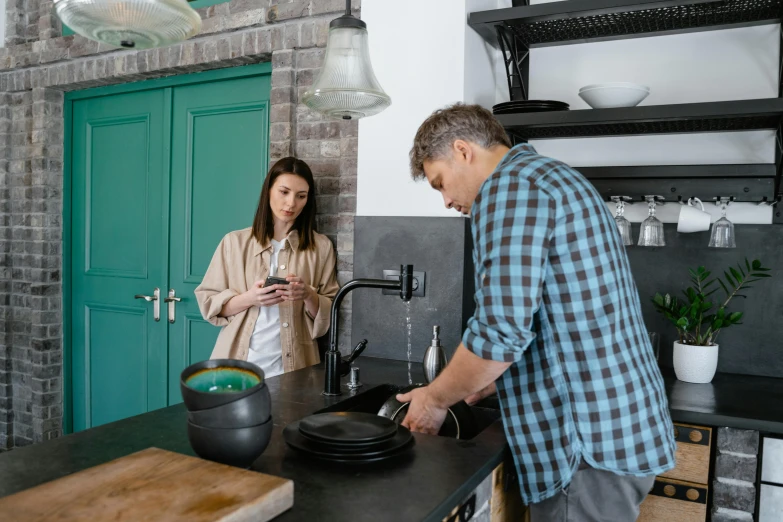 the woman stands in a kitchen by the counter looking at plates