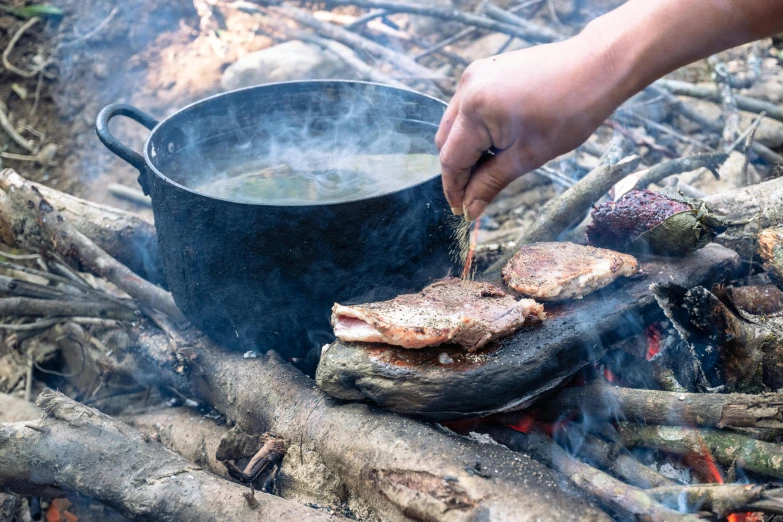 a person is cooking on the stove over a campfire