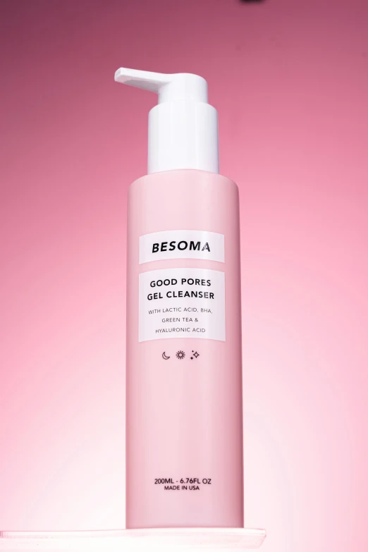 a pink bottle of skin care sitting on a pink surface