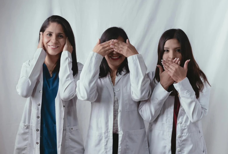 three woman standing with their hands covering their eyes