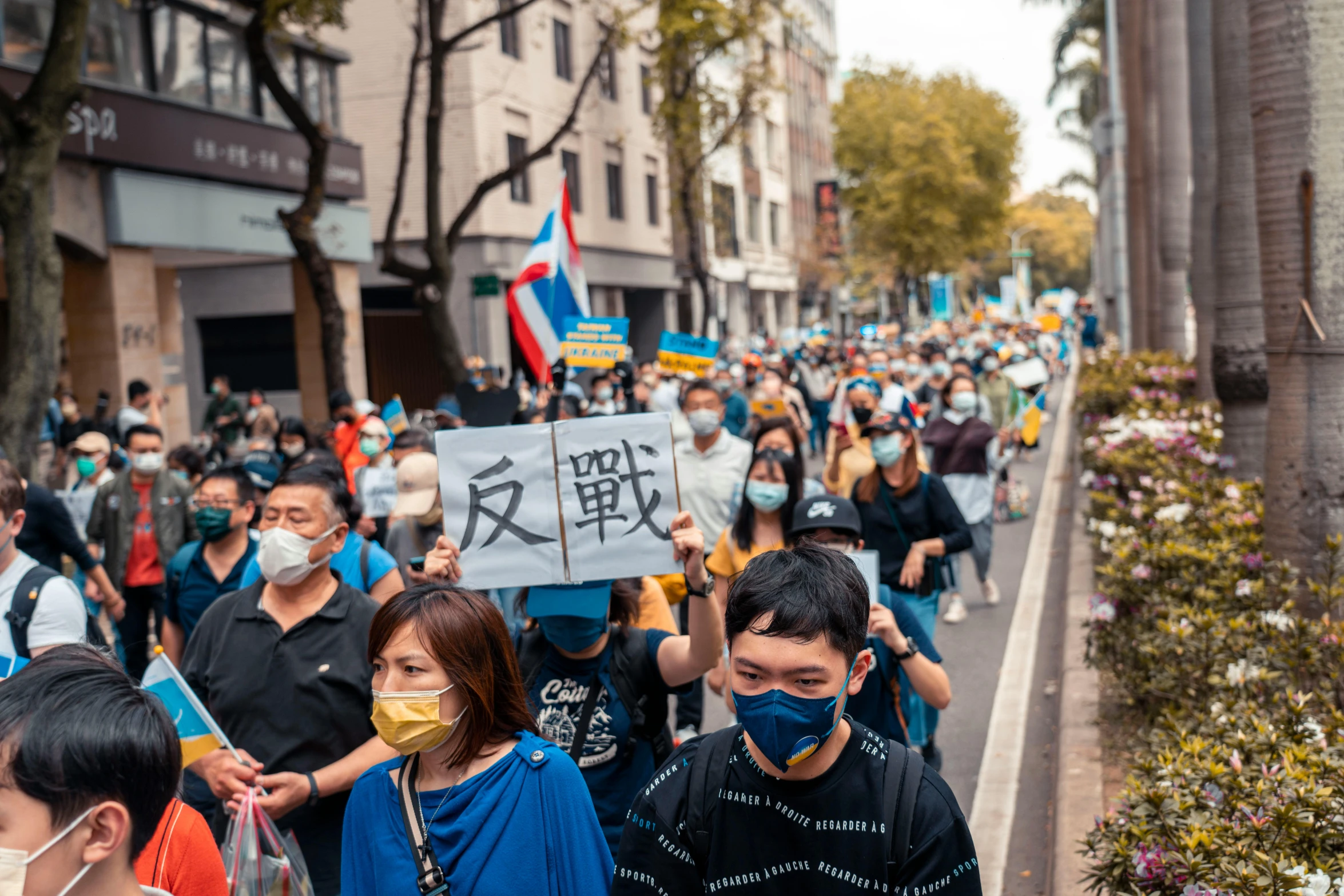 a crowd of people with face masks holding signs