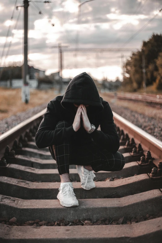 a person sitting on a set of stairs covering their face