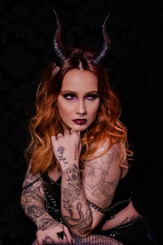 a woman with horns and piercings poses for the camera