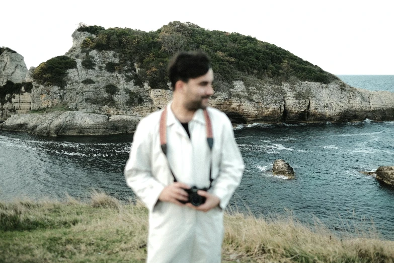 a man in a white suit is standing by the water