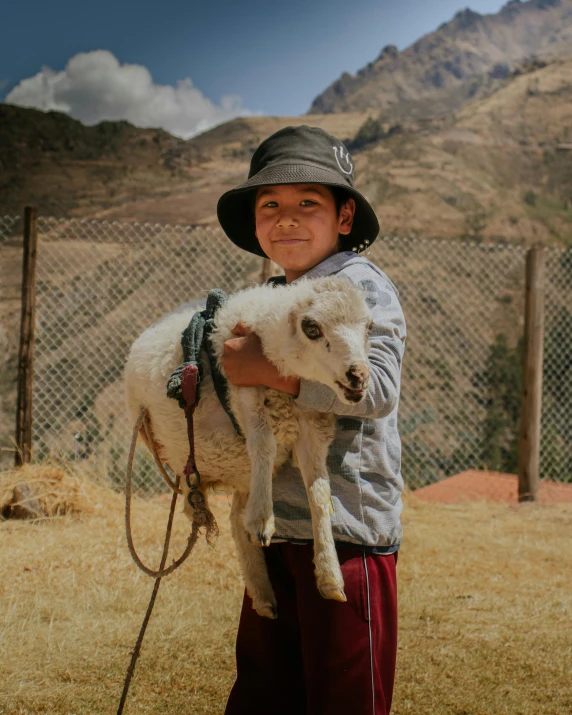 the young child is smiling and holding his shaved goat