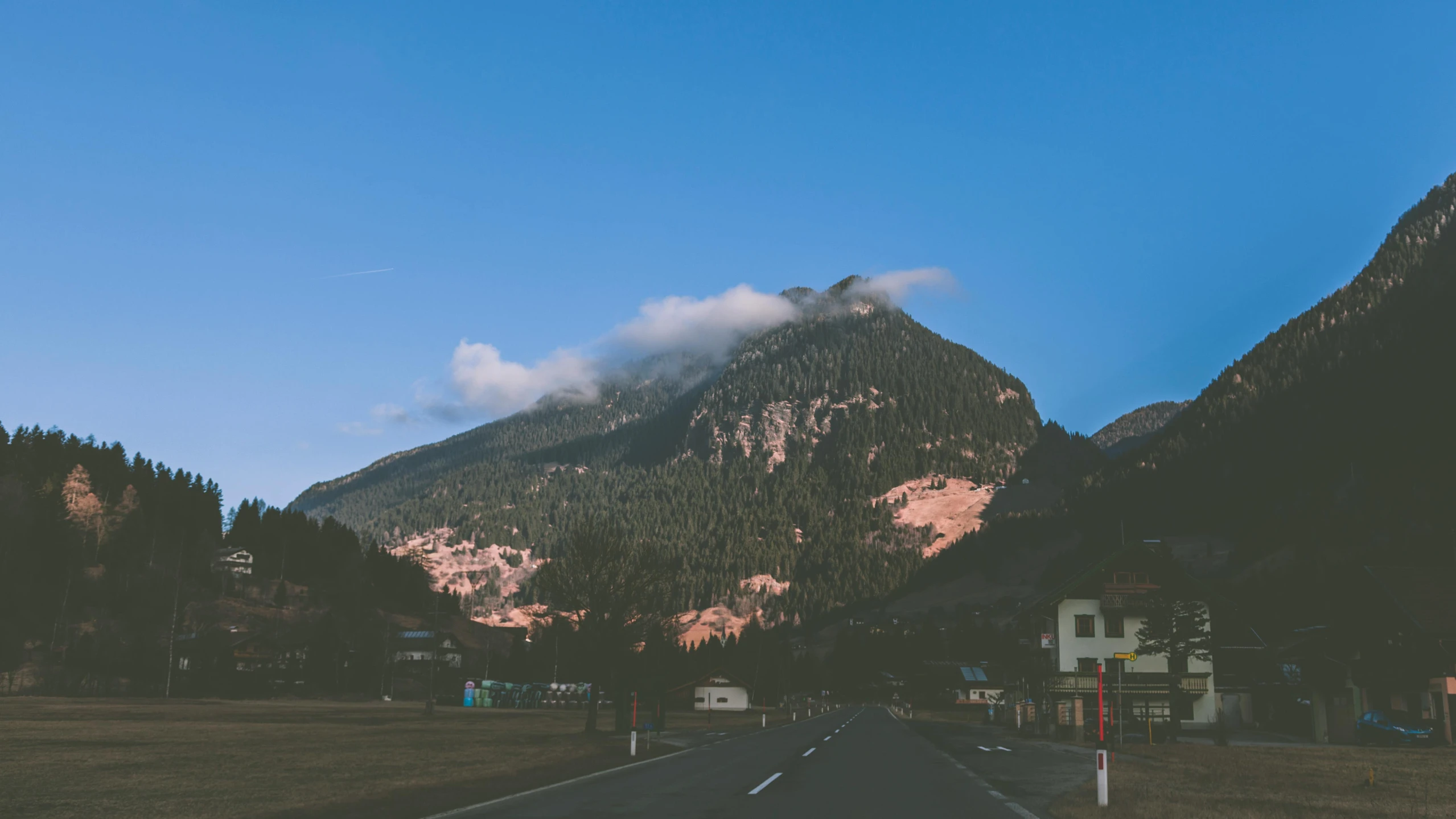 a road going towards some mountains next to trees