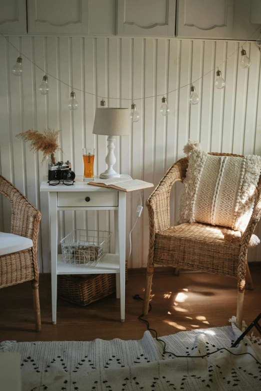 a white table with a table lamp, a brown chair and a white nightstand