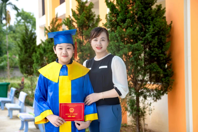 two people wearing graduation clothes and holding a book