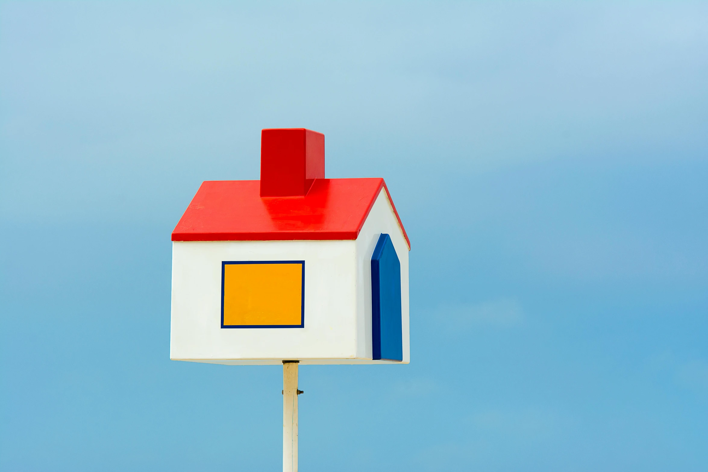 this colorful birdhouse is on a wooden stand