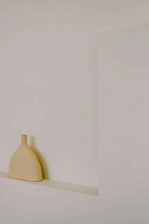 a white vase sitting on the wall in a corner