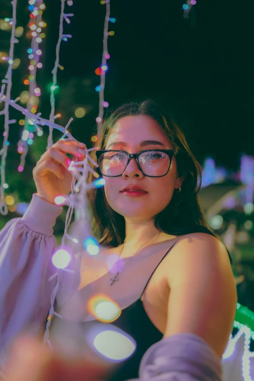 a young woman is holding lights while she is wearing glasses