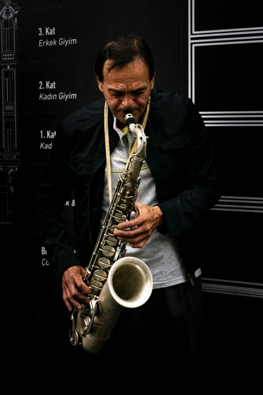 a man holding onto a saxophone as it sits against a wall