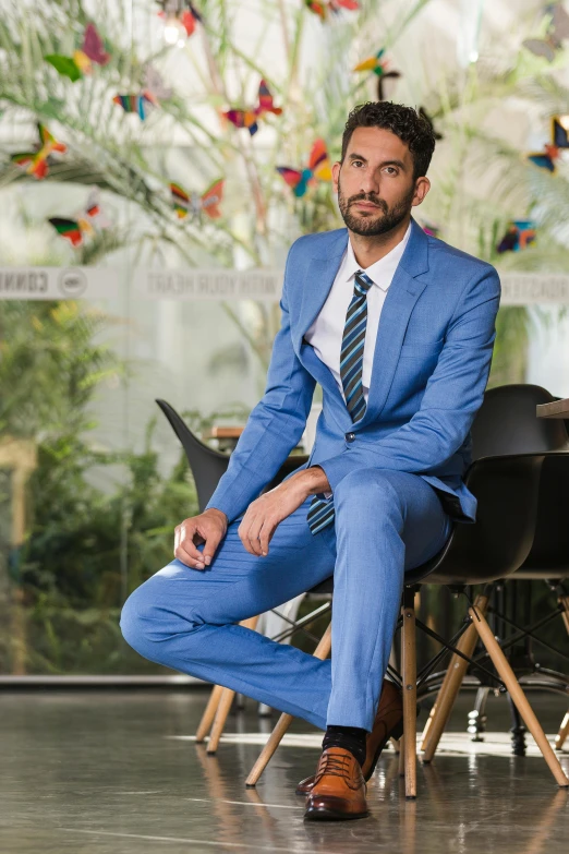 a man in a suit sitting on a chair with his legs crossed