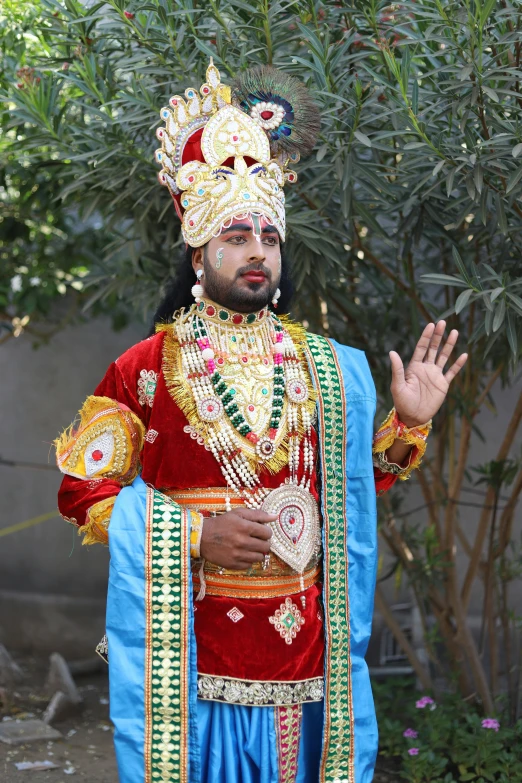 an elaborately decorated man is standing with his hand out to the side