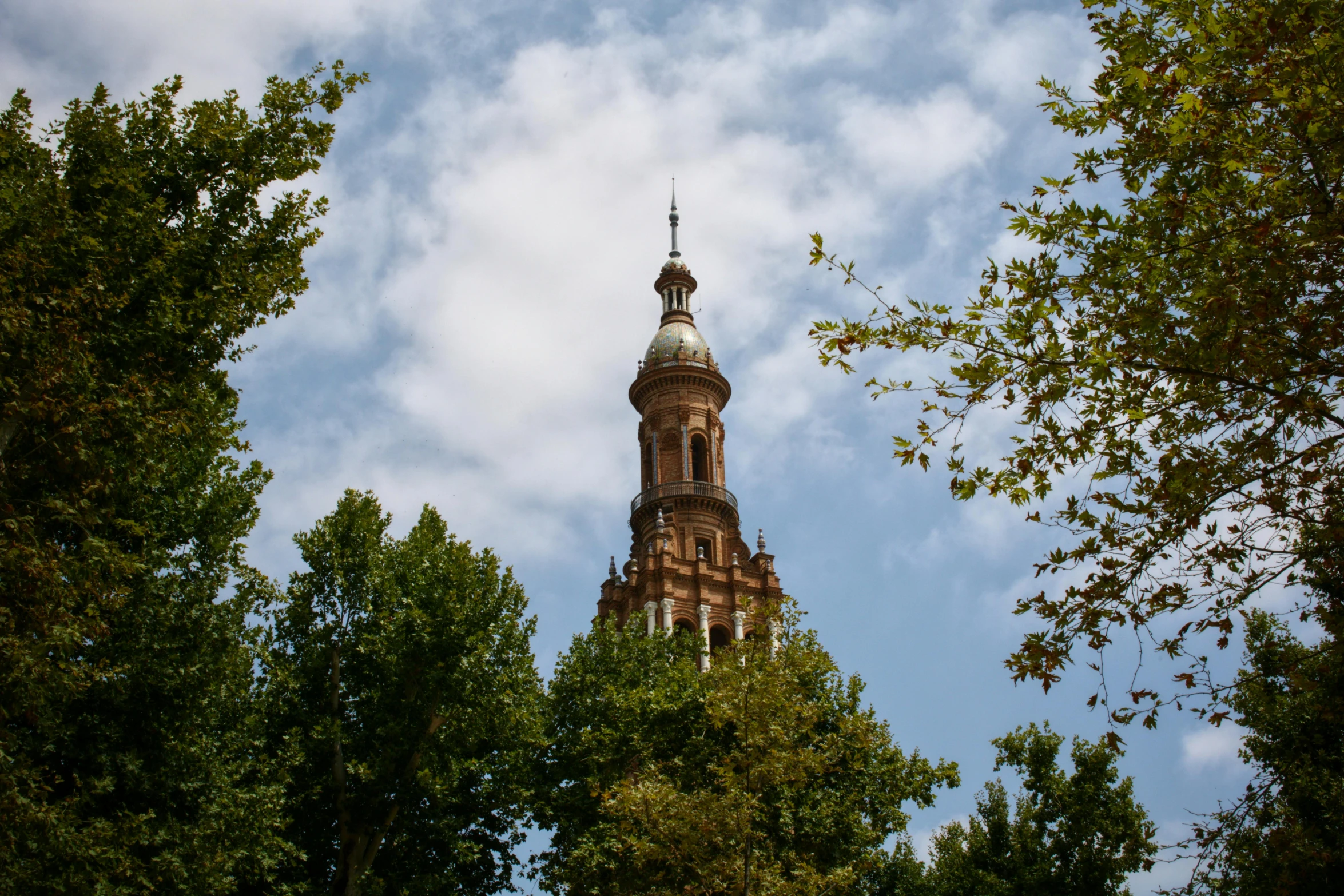 the steeple of a church spire surrounded by trees