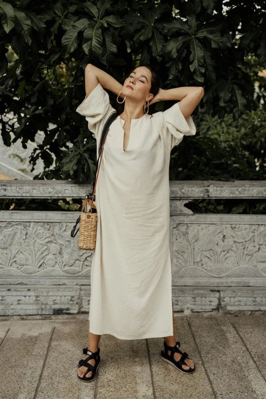 woman in white dress stretching while standing on a balcony