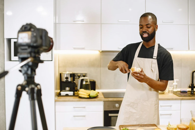 a man in an apron preparing food and making pictures on the camera