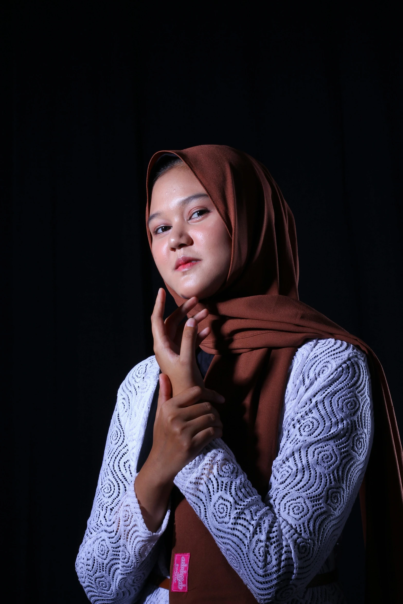 a woman standing with her hands folded near her face