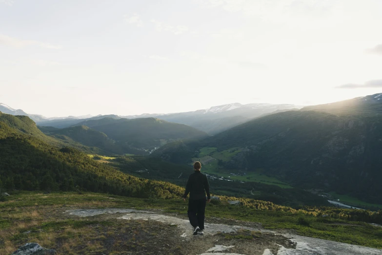 man with arms outstretched looking at mountains and valleys