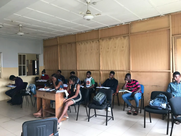 group of students sit in chairs listening to their teacher