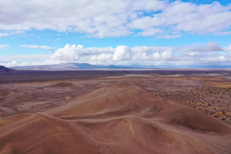 an aerial view of a mountain range with hills and clouds