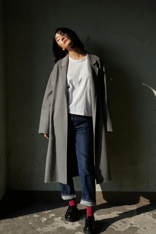 a young woman is posing near a white wall