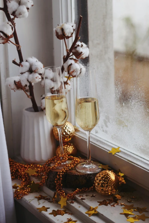 two glasses of champagne sitting next to each other on a window sill