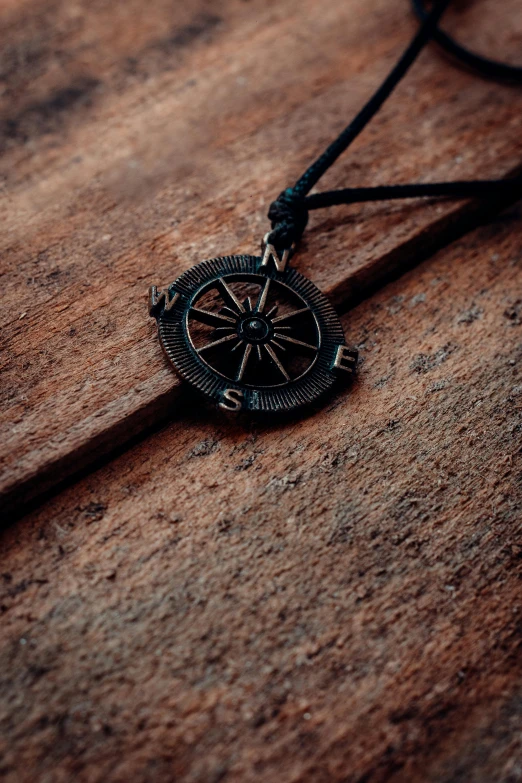 an old compass hangs from a cord on a wooden table