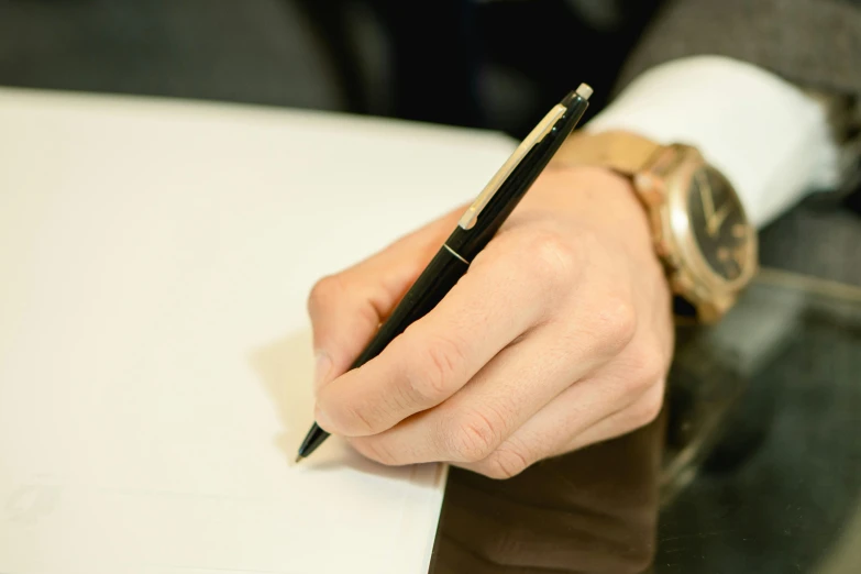 a person holding a pen over a piece of paper