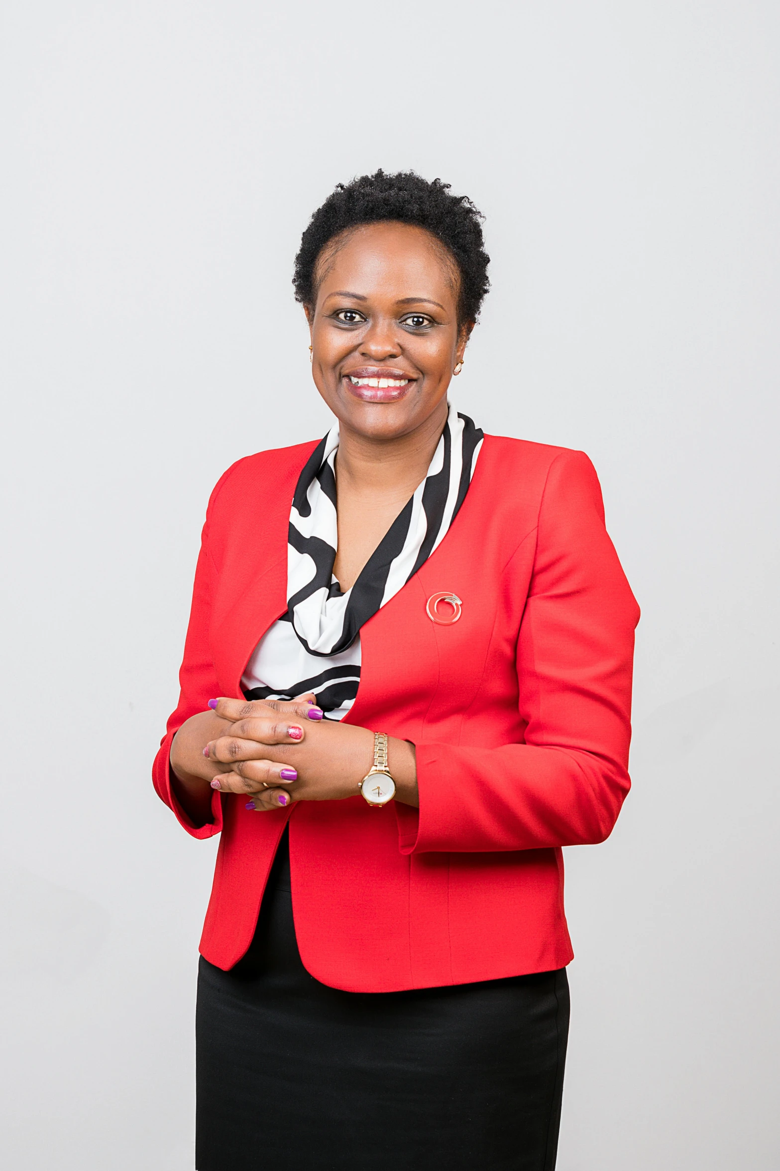 a woman in a red blazer standing in front of a white wall