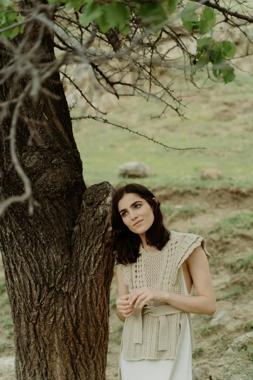 an old woman standing next to a tree