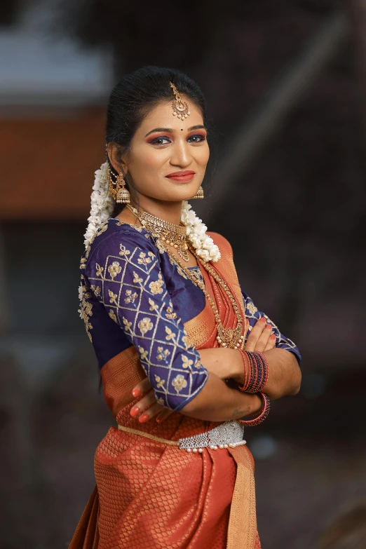 a woman dressed in a orange and blue sari with jewelry