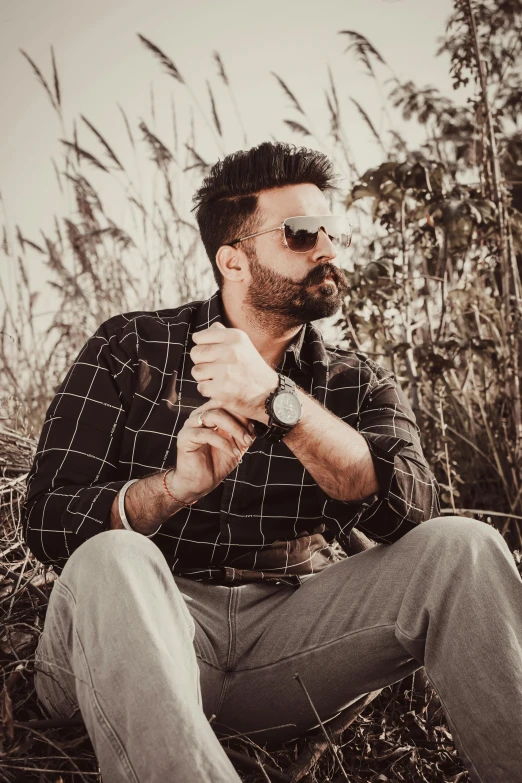 a man sitting on the ground near tall grass