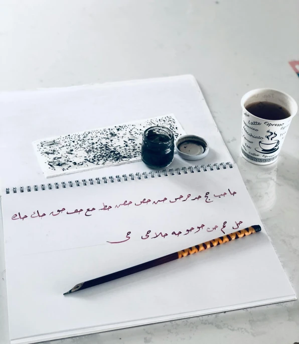 a pen, ink, paper and coffee are sitting on a desk