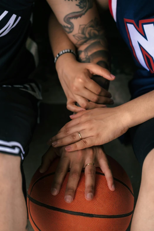 some people stack their hands on top of a basketball