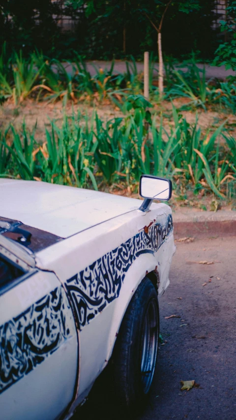 the front end of a white car with a street light