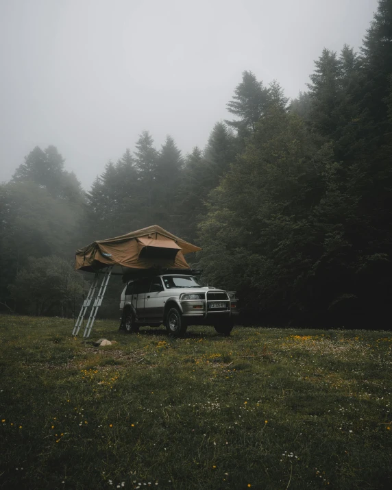 an off - road camper sits in front of its tent in a foggy field