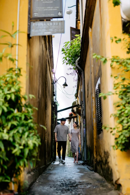 the two people walk down a narrow alley way