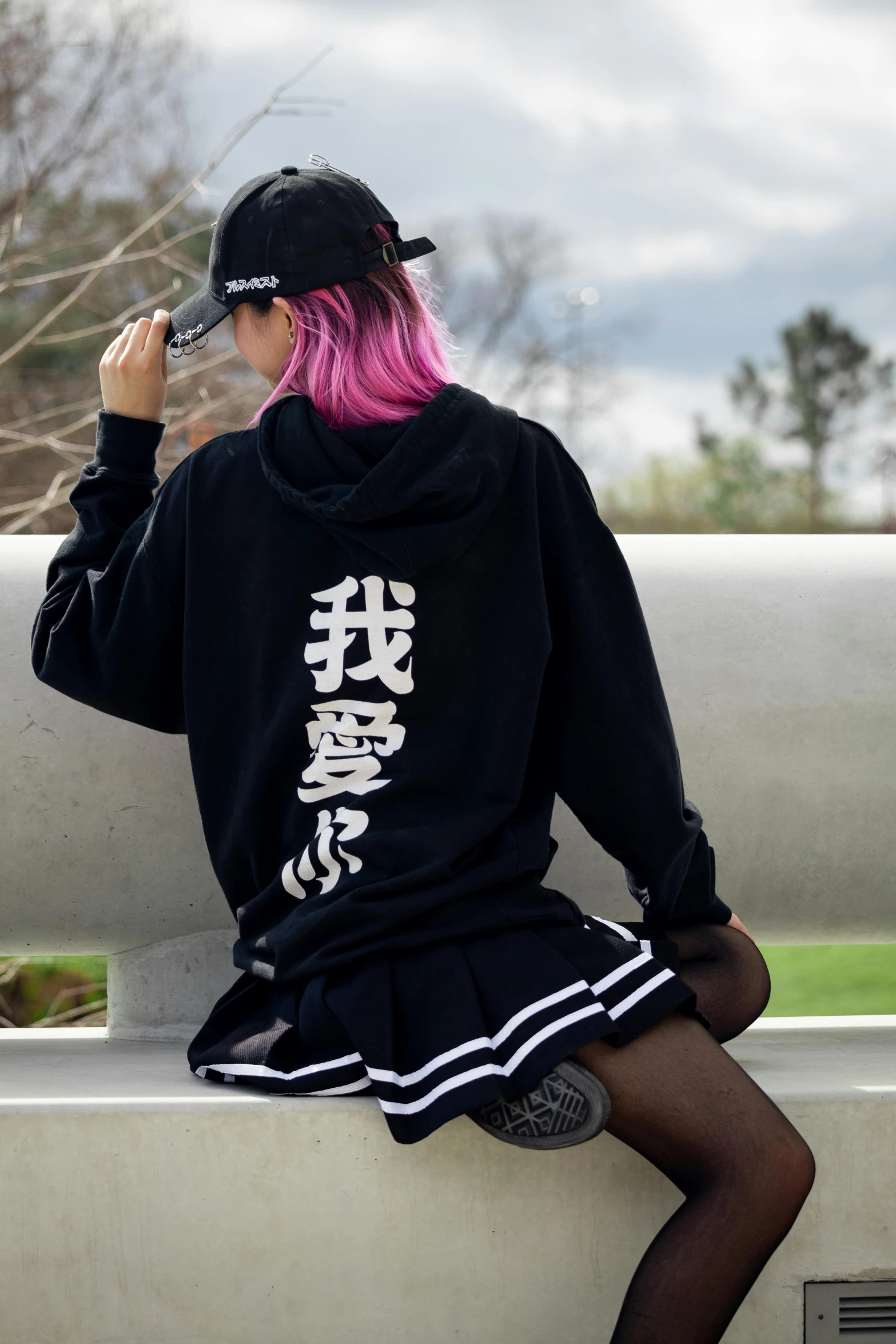 a woman sitting on a bench wearing a black hoodie