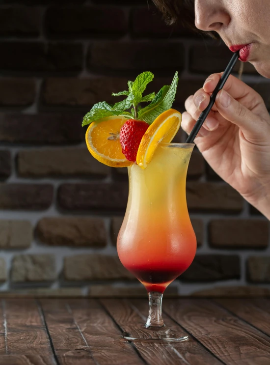 a woman is holding a straw and strawberries with a drink