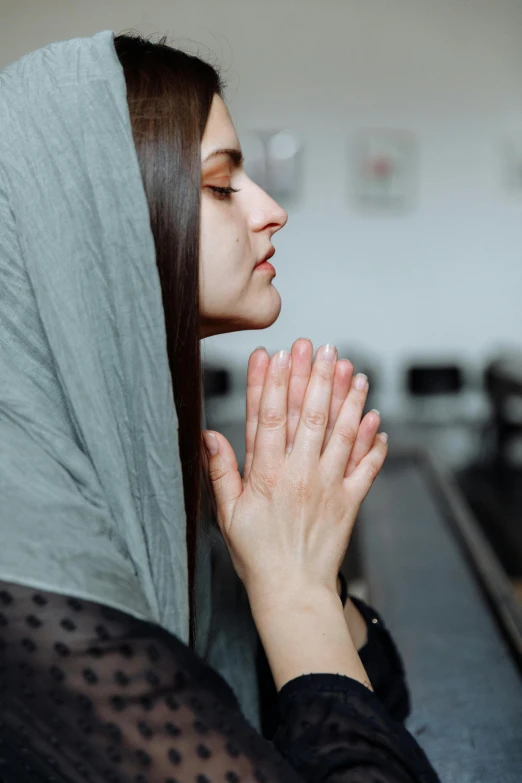 a young woman wearing a hooded sweatshirt praying