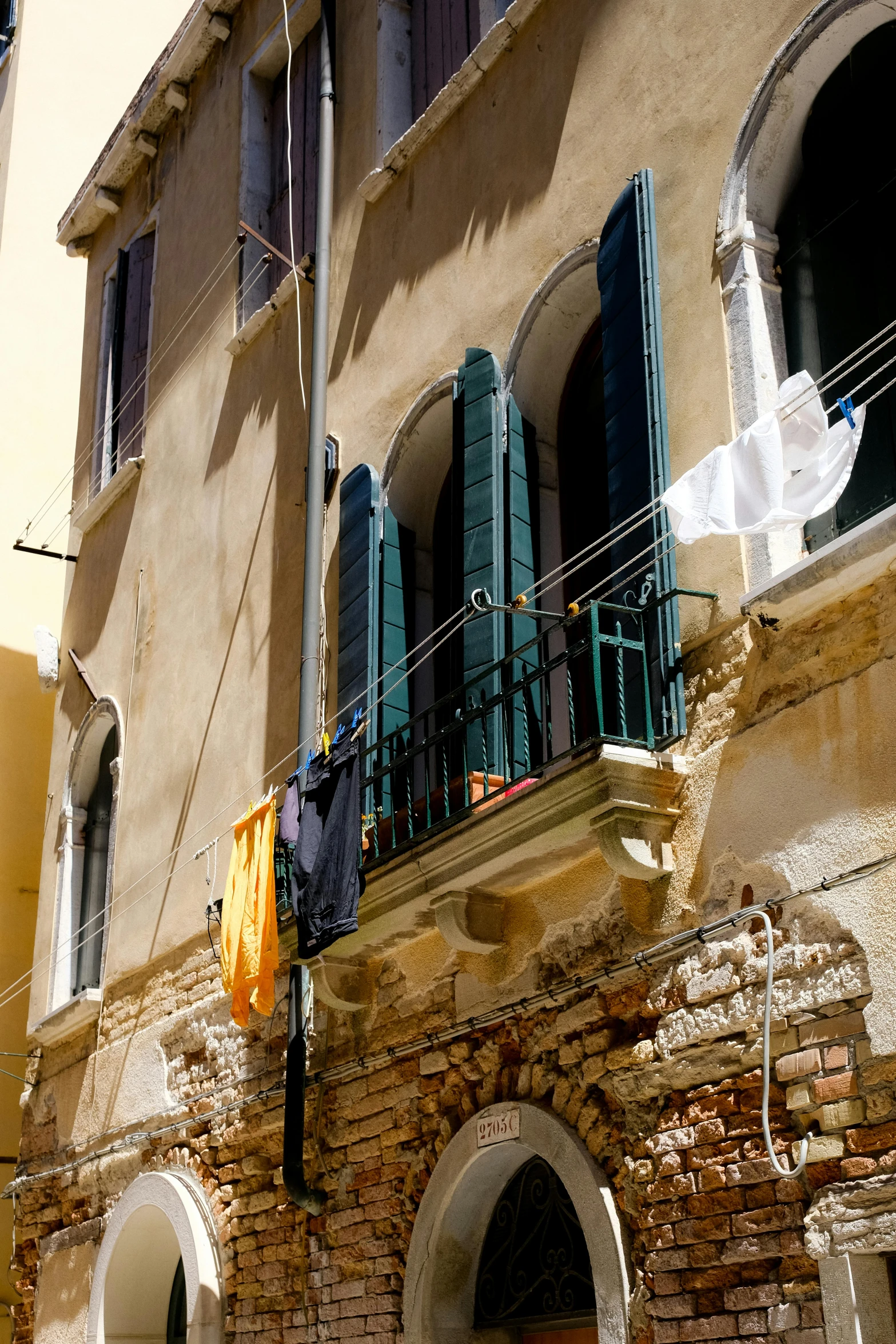 some green shutters are hanging from the balcony