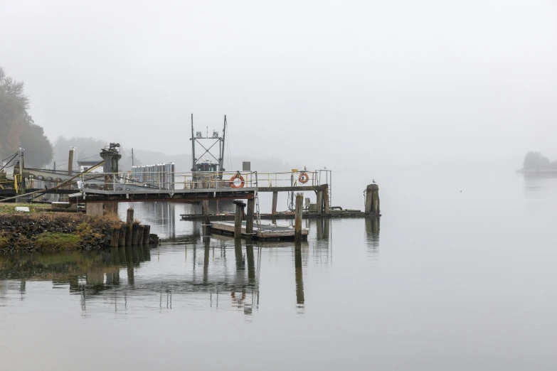 the boat is in the calm lake on a foggy day