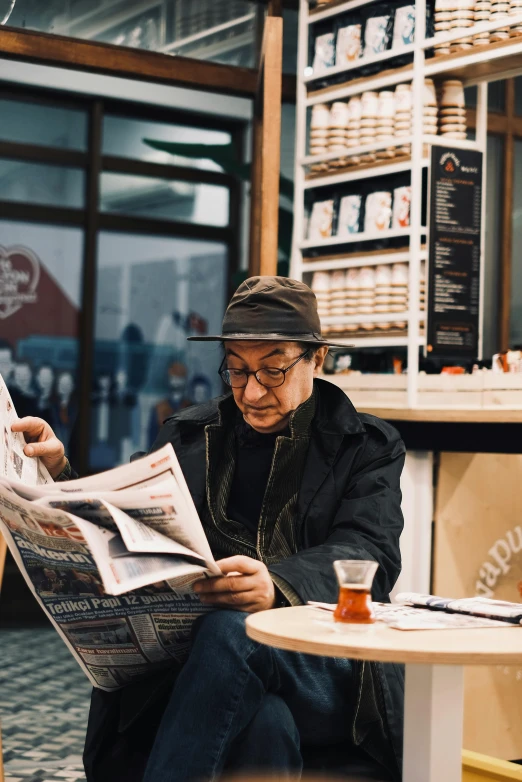 a man is sitting on the ground reading a newspaper