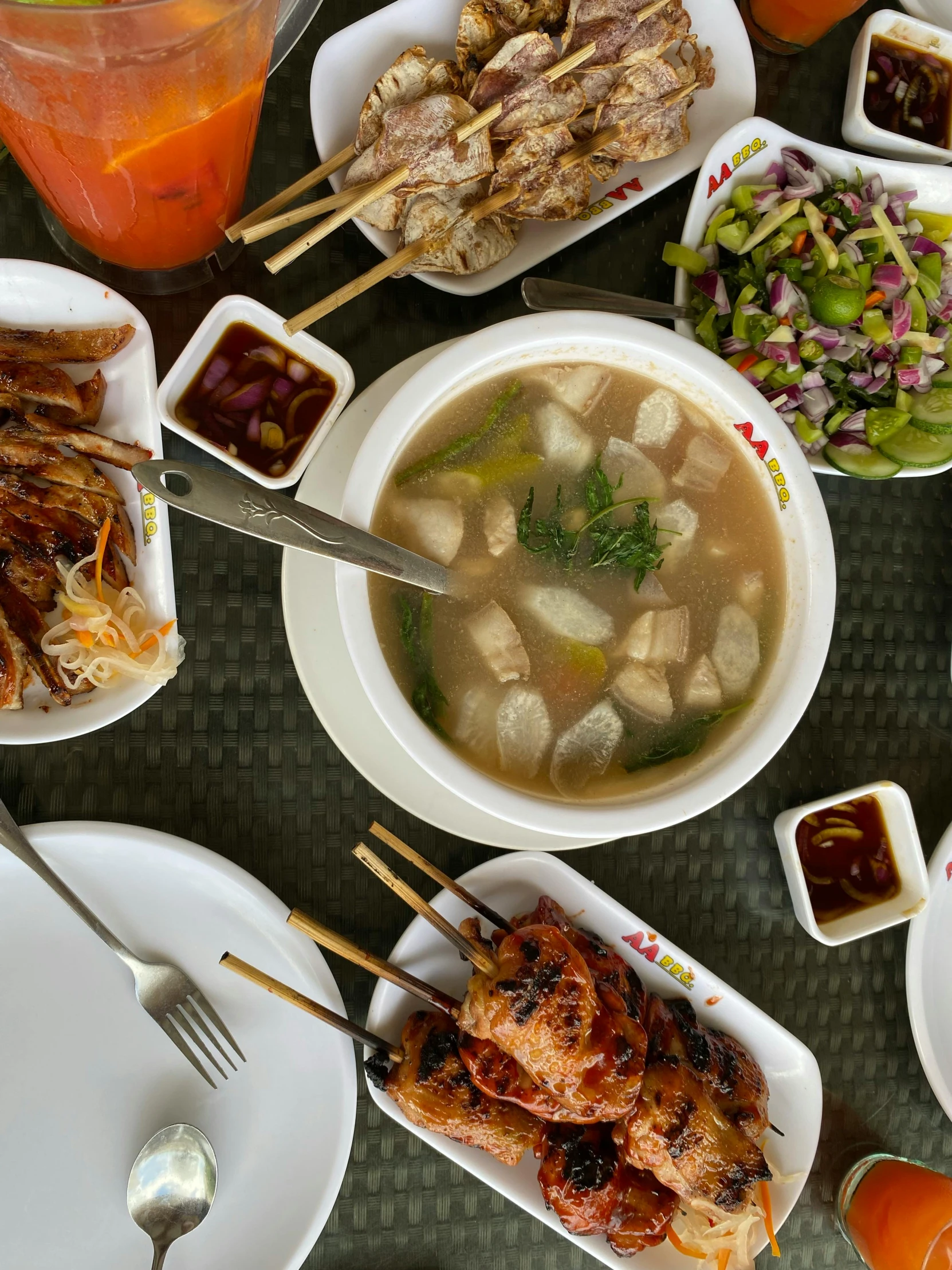 a variety of foods on the table, with drinks and dipping sauces