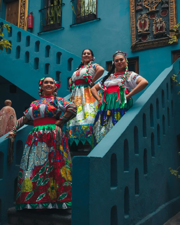 women in colorful dresses standing on steps in a town