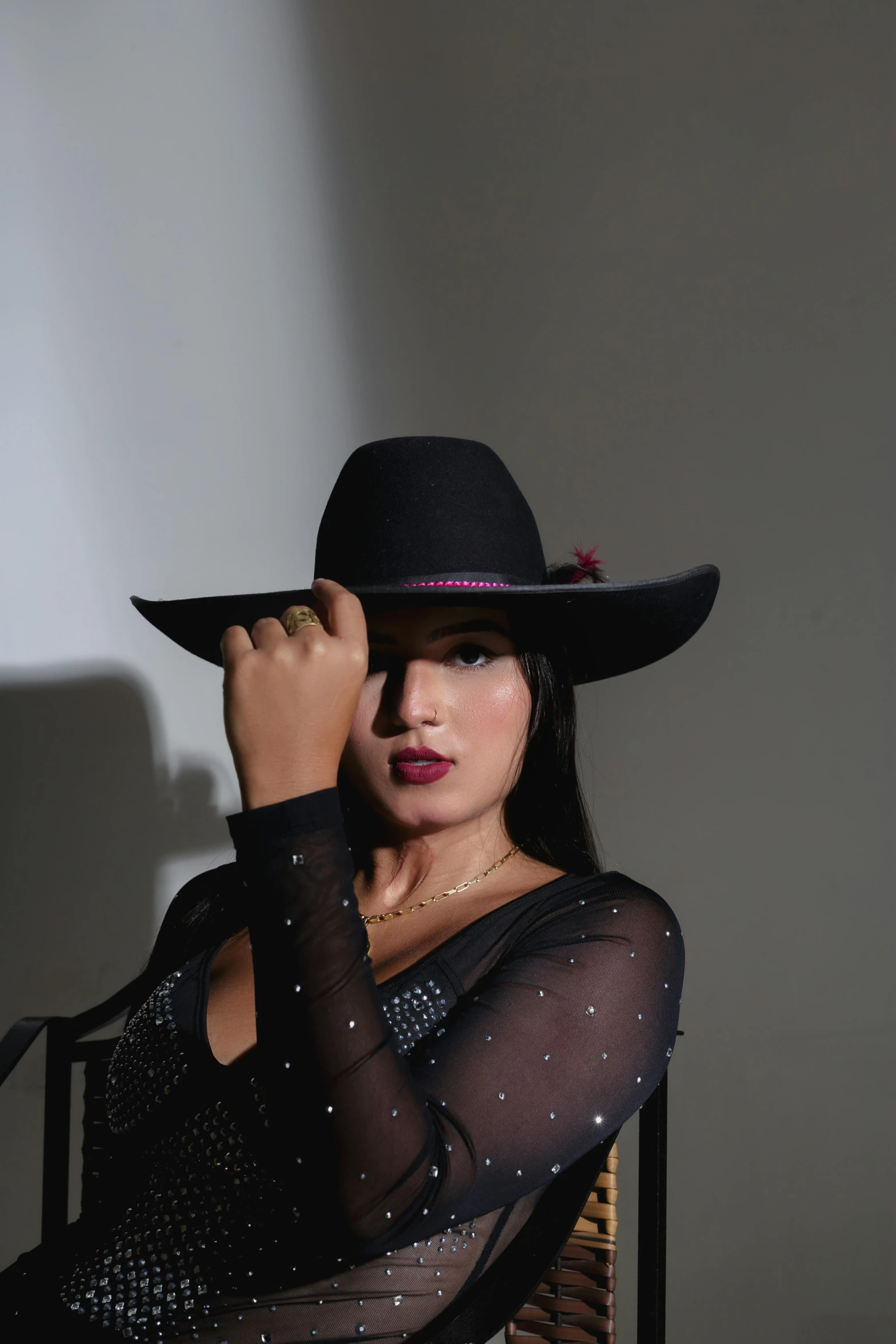 woman in a black hat posing in front of white wall